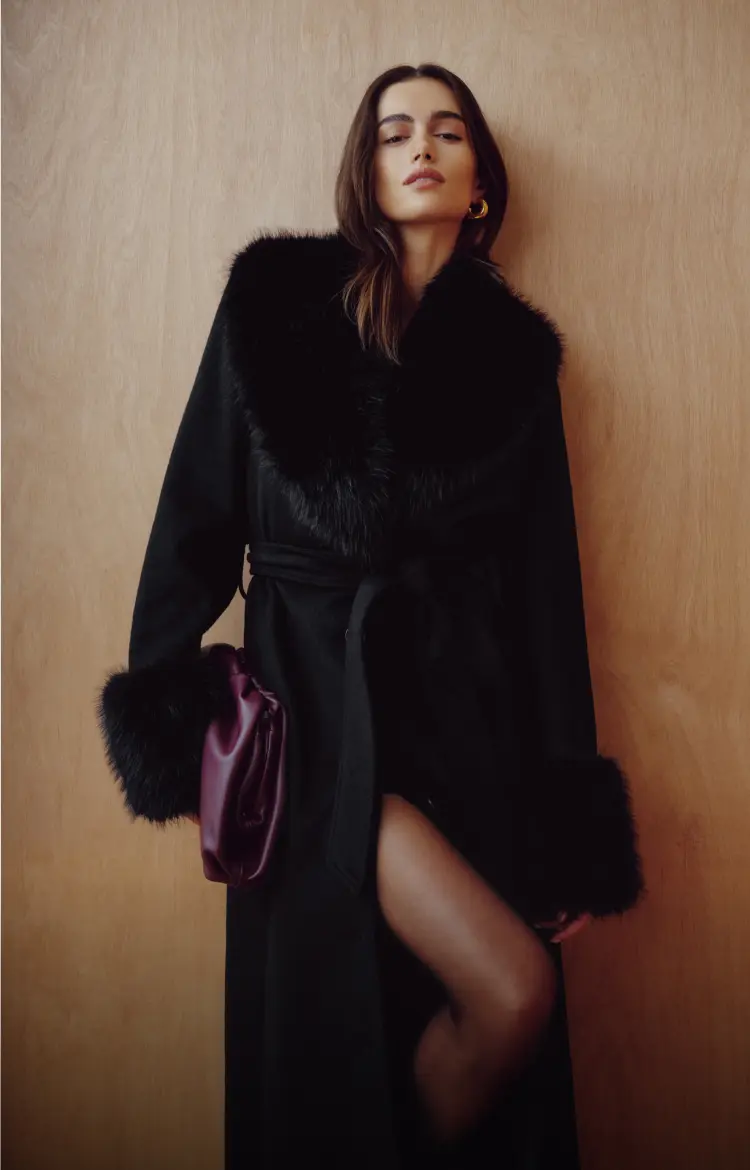 Model is wearing a black faux fur trim woollen coat.