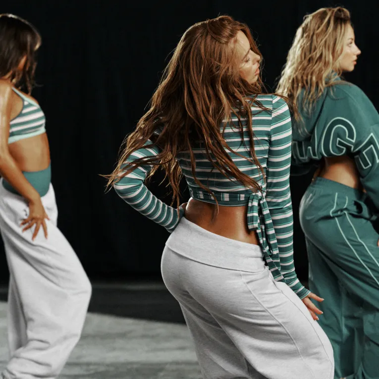 Models pose in a mix of teal, grey, and white active outfits.