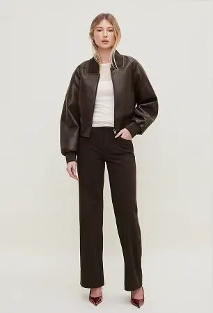 Model is wearing a brown faux leather bomber jacket and black jeans.