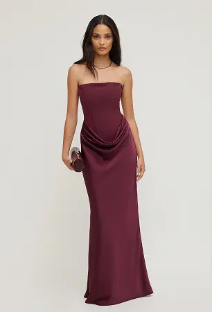Model is wearing a burgundy corset dress.