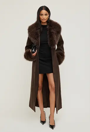 Model is wearing a brown faux fur trim wollen coat and a black mini dress.