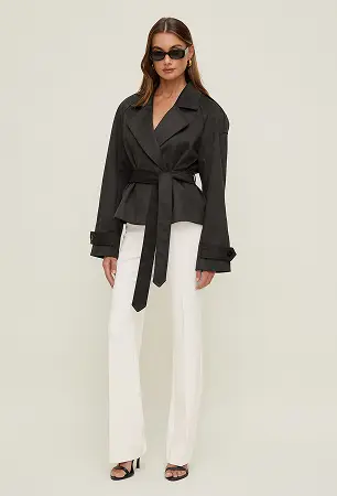 Model is wearing a brown faux suede jacket and white pants.