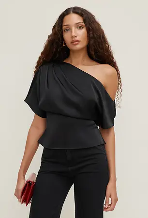 Model is wearing a black off shoulder blouse and black slim jeans.