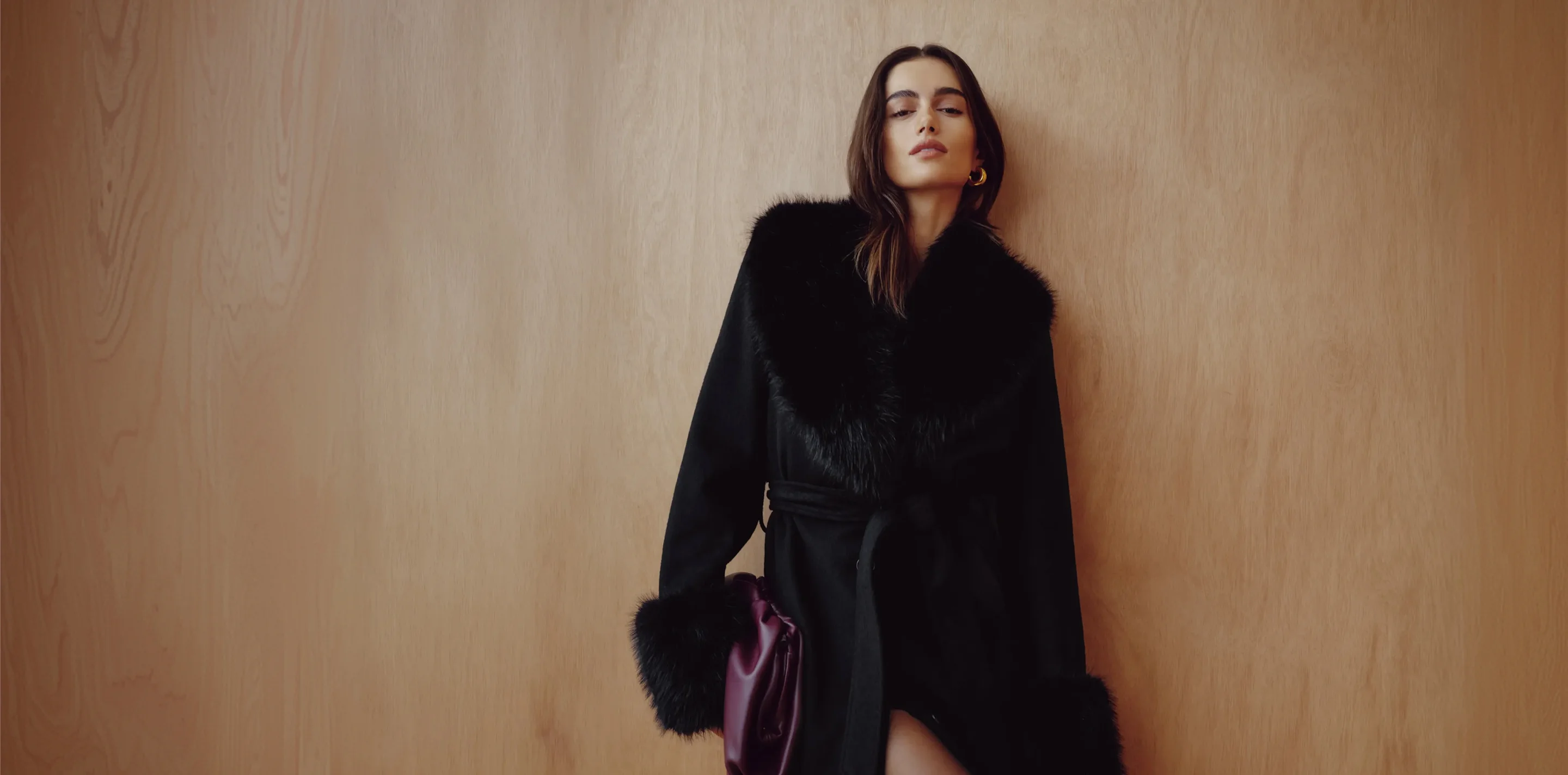 Model is wearing a black faux fur trim woollen coat.