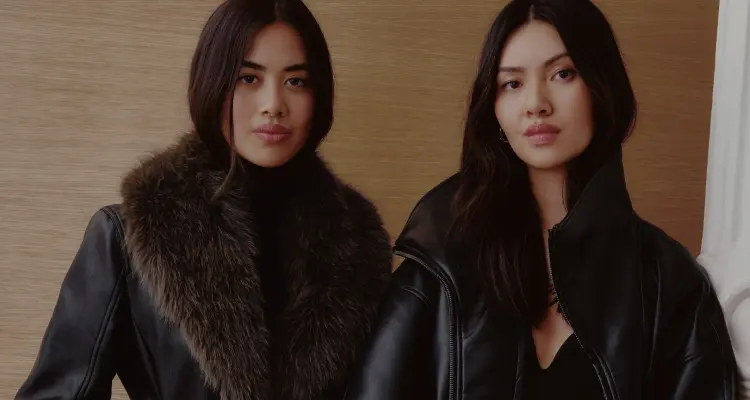 Model is wearing a black faux fur trim coat.