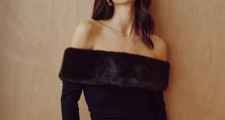 La mannequin porte une minirobe noire à bordure en fausse fourrure.