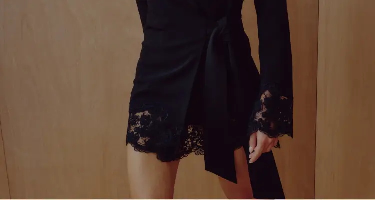 La mannequin porte une minirobe noire à bordure en dentelle.